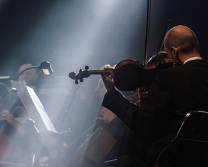This captivating photo features an orchestra in full swing, with a talented violinist taking center stage. The lighting and atmosphere of the setting create a mystical and enchanting mood - 244123607