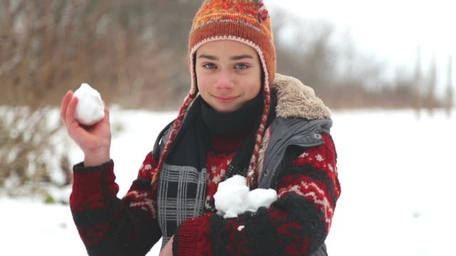 Teen boy sculpts and throws a snowball into the camera. Child boy throws a snowball into the camera.
