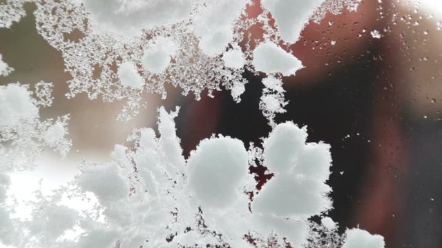 The boy wipes the snow and draws on the frozen glass.Portrait of a child who looks into the house through the window in the winter.

