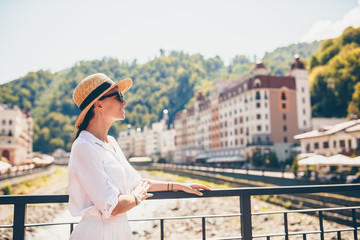 Fototapeta na wymiar Happy girl at hat on the embankment of a mountain river in a European city.