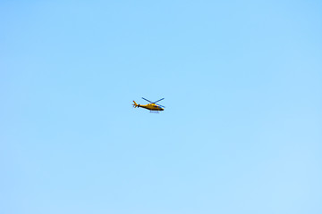 The yellow helicopter flying in the sky
