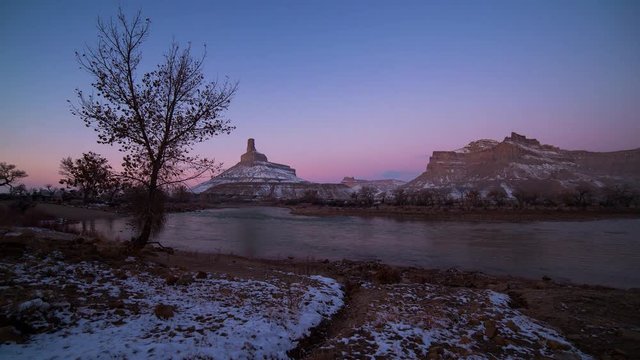 Time lapse of alpenglow changing colors in the sky over the desert next to Green River in Utah during winter.