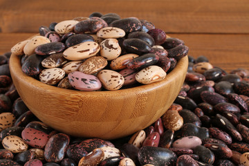 Raw purple, pink, beige with brown speckled kidney beans on brown wooden table. Closeup