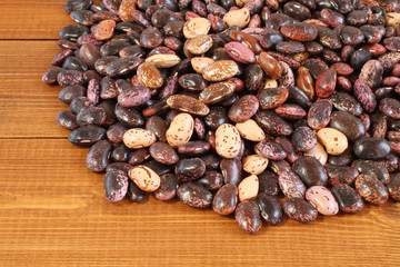 Raw purple, pink, beige with brown speckled kidney beans on brown wooden table. Closeup