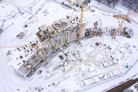 aerial top view of city construction site. tower cranes for building of new apartments under snow in winter