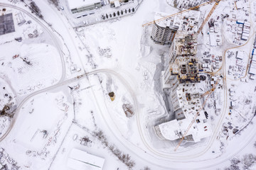 city construction site covered with white snow. building of new apartments in winter, aerial view
