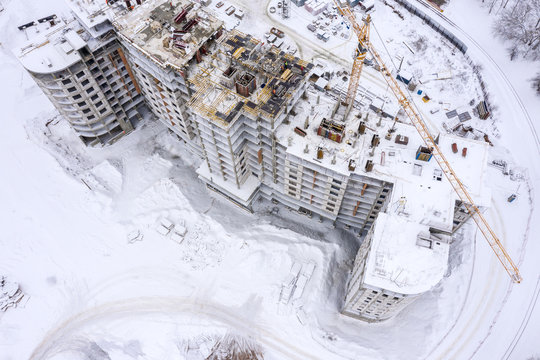 building under construction in snow. high tower cranes at construction site in winter. aerial top view