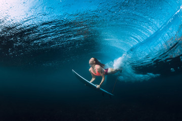Surfer woman dive underwater with under barrel wave.