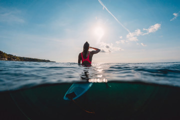 Surfer woman see waves with surfboard. Surf girl in ocean.