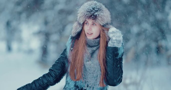 Girl walks in the winter. It is snowing and the woman is smiling. Portrait view.