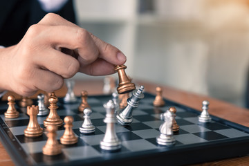 Businessman playing chess game beat opponent with strategy concept.