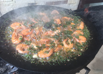 Food concept designed as beautiful lunch: prawns and parsley are cooking and mixing in the black pan and hot water over an open fire