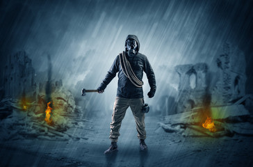 Fototapeta premium Destroyed place after a catastrophe with man in gas mask and weapon on his hand 