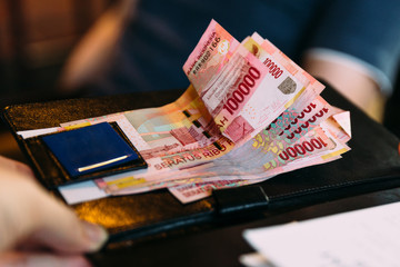 Man is paying in cash with Indonesian banknotes. Indonesian currency banknotes payment method.