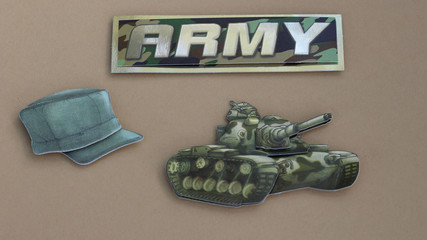 army sign tank and army hat laying flat on a tan background 