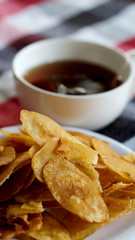 Sweet crispy banana chips serve with hot tea on white dish and thai style cloth with space for write wording, a way to preserve agriculture fruit and adding value to growth business export worldwide.