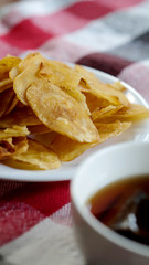 Sweet crispy banana chips serve with hot tea on white dish and thai style cloth with space for write wording, a way to preserve agriculture fruit and adding value to growth business export worldwide.
