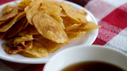 Sweet crispy banana chips serve with hot tea on white dish and thai style cloth with space for write wording, a way to preserve agriculture fruit and adding value to growth business export worldwide.