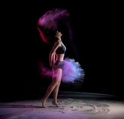 Young woman shaking hair and throwing chalk while dancing 