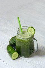 Healthy green smoothie with ingredients on white wooden background