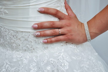  Bride standing with hand on hip in her wedding dress and engagement ring-  flowers on wedding dress 