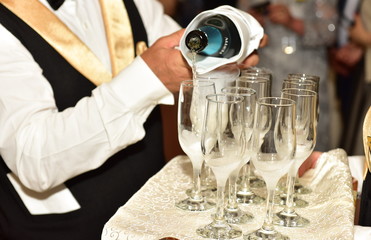 Waitress holding a dish of champagne and wine glasses at some festive event,