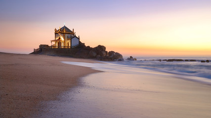 Fototapeta na wymiar Landscape over the beach of miramar with view to chapel of senhor da Pedra at blue hour