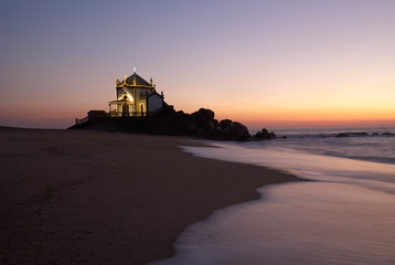 Landscape over the beach of miramar with view to chapel of senhor da Pedra at blue hour