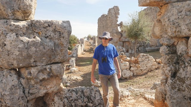 Young man tourist with binoculars exploring ancient city