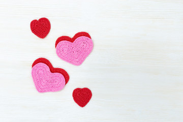 Knitted hearts on white wooden background with copy space. Flat lay. Top View.