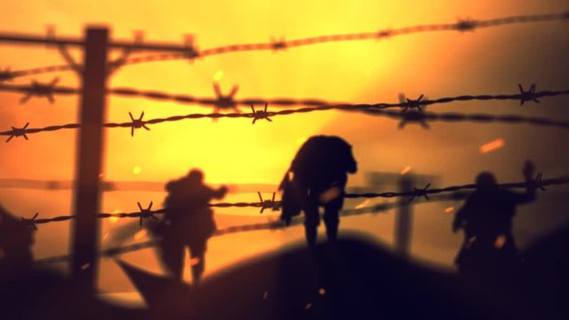 Barbwire Zombies at Sunset 4K Loop features zombie silhouettes walking forward viewed through strands of barbed wire with moving clouds and particles.