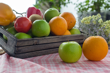 Orange and apple in a wooden crate. Fresh fruit on a wooden table with a cloth. Eating fruit helps to lose weight. fruits and vegetables in wooden box on table in kitchen. Selective focus.