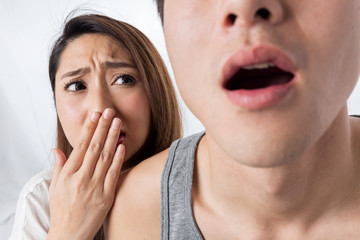 男性の口臭に口を塞ぐ女性