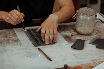 Close up of master making leather wallet with brush and glue. Handmade master at work in local workshop. Handmade concept. Top view