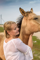 Portrait of a blonde girl with a horse in summer.