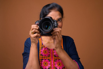 Mature beautiful Indian woman photographer using DSLR camera