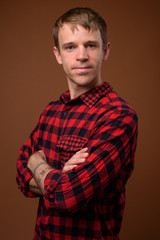 Fototapeta premium Man wearing red checkered shirt against brown background