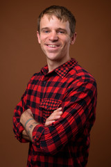 Happy man wearing red checkered shirt against brown background