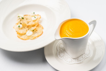 Pumpkin and carrot soup with cream with croutons on the white background