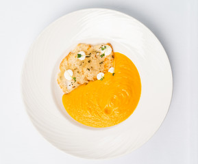 Pumpkin and carrot soup with cream with croutons on the white background