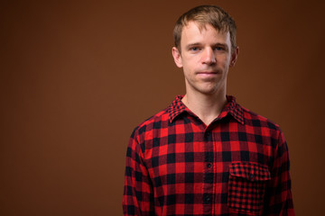 Man wearing red checkered shirt against brown background