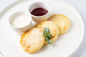 Cottage cheese pancakes sour cream and jam,  syrniki on white background