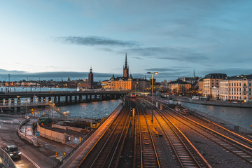 Obraz na płótnie Canvas Evening cityscape with subway train crossing the bridge of Gamla Stan, Stockholm, Sweden. City hall and cathedral in background