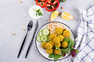 Traditional middle eastern homemade dishes falafel, pita, served with vegetables and spices on concrete background table. Top view