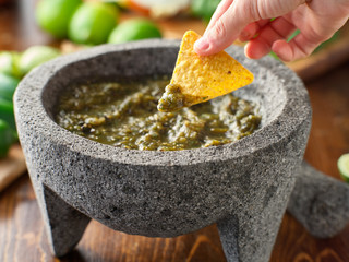 dipping a tortilla chip in mexican salsa verde - obrazy, fototapety, plakaty