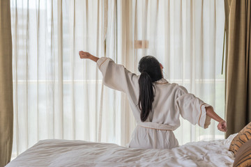 Good morning wake-up with Asian woman relaxing in hotel room