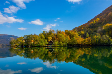 Fototapeta premium The beautiful reflection of the sky and hills in the water and small wooden house