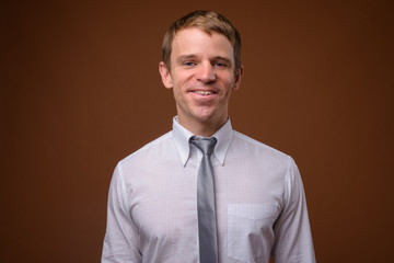 Businessman wearing white shirt against brown background