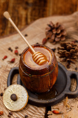 Honey wooden spoon immersed in a barrel of fragrant fresh honey.