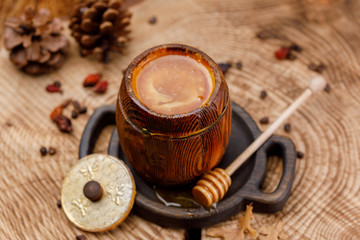Barrel with fresh delicious honey and honey stick on a wooden saw.